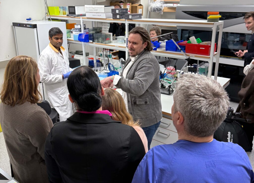 Sjukvårdsministern och kollegor vid rundtur på laboratorium.